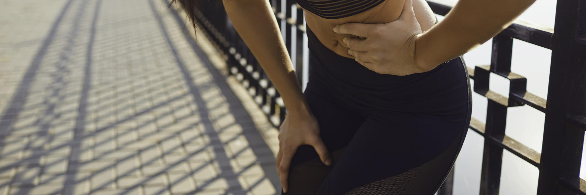 Athletic woman caught by pain in abdomen while running.