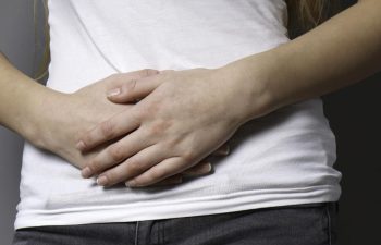 A young woman holding her both hands on abdomen.