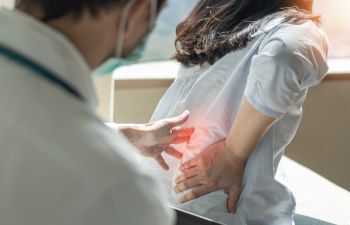 A doctor consulting a woman with a lower back pain caused by nerve compression syndrome.