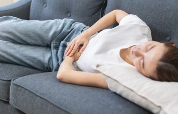 Sick asian young woman in pain, hand holding belly, stomach pain from food poisoning, girl hurt abdomen ache and digestive problem, gastritis or diarrhea. Health care inflammation, abdominal problem